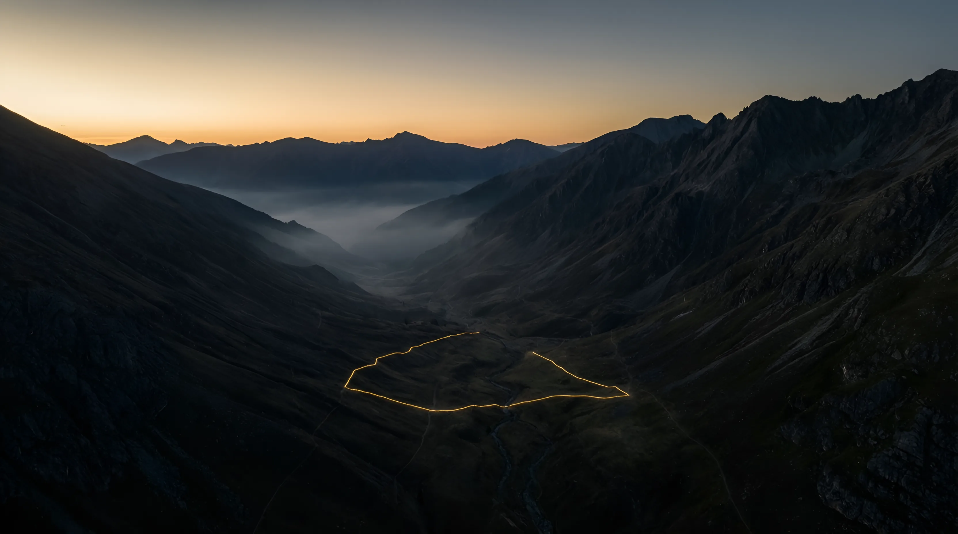 Dark mountain terrain at dusk with a gold survey boundary traced around a valley